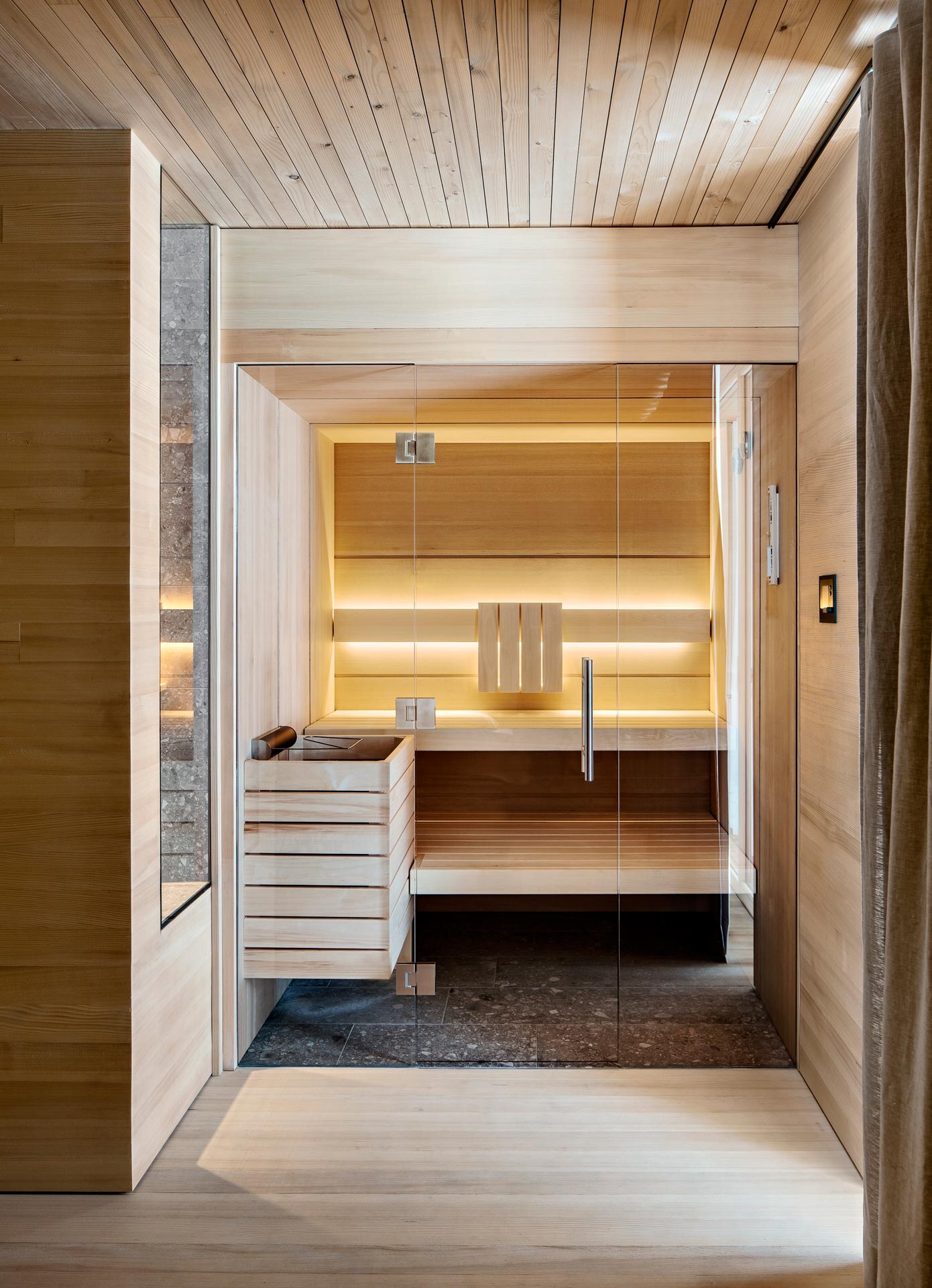 Beleuchtete Sauna en suite in puristischem Design aus hellem Hemlockholz im Chalet des Peterhof auf der Alpe Furx.