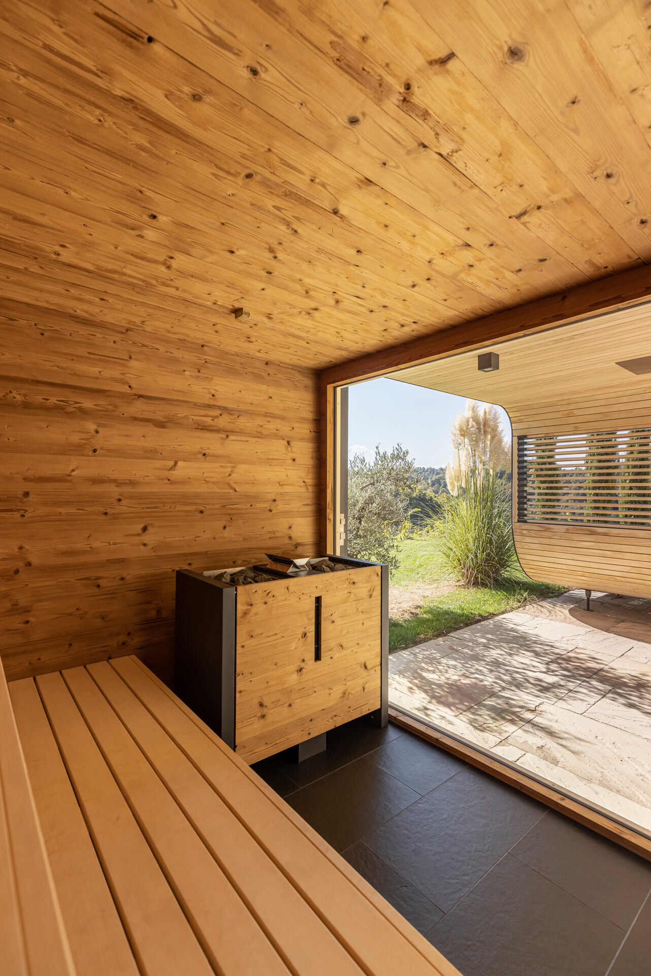 Sauna im Poolhaus mit großem Panoramafenster, harmonisch eingebettet in die Architektur und den mediterranen Garten.