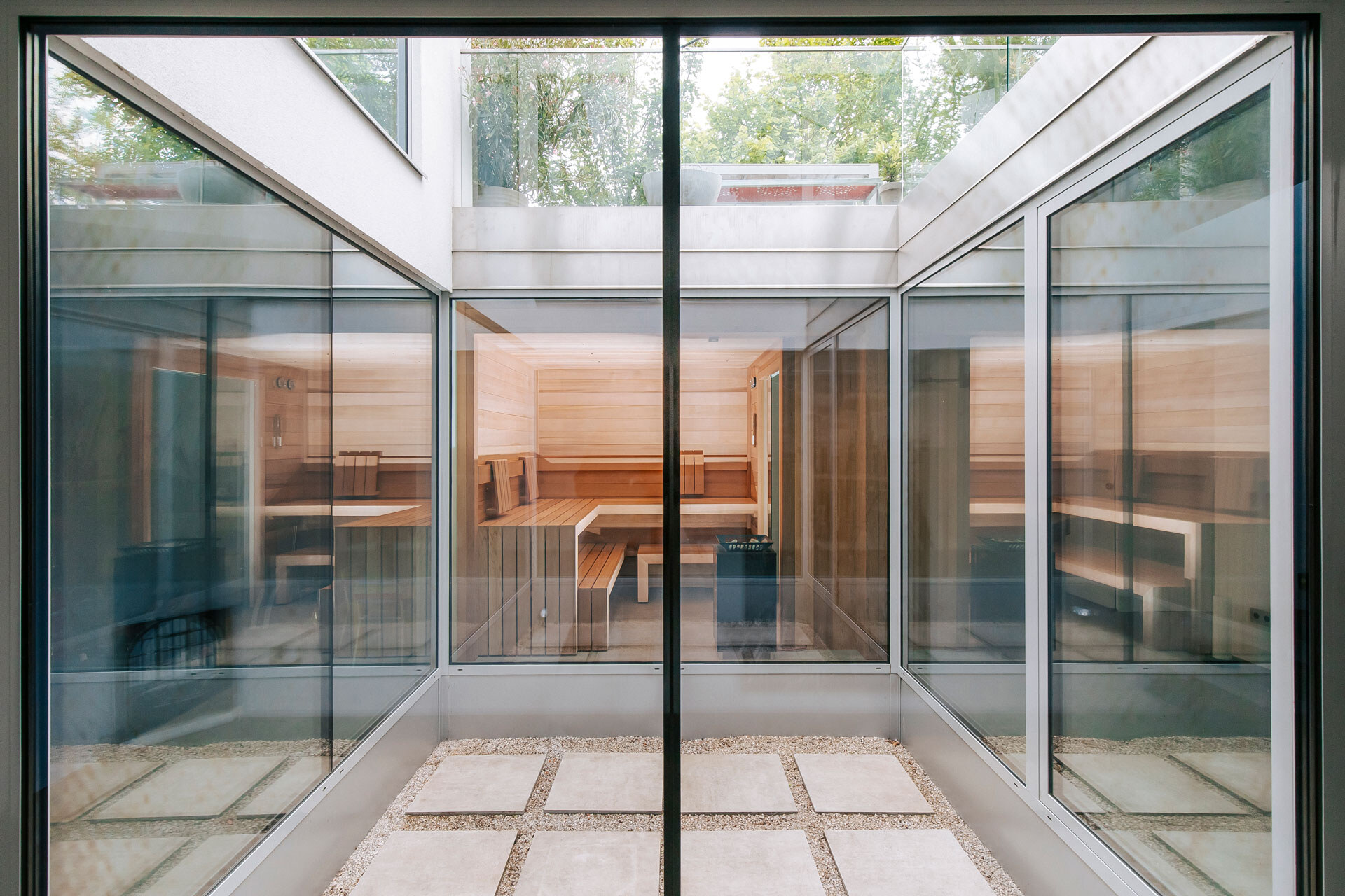 Rundum verglastes Atrium mit Metallverkleidung und beleuchteter Sauna aus Zedernholz mit großem Panoramafenster.