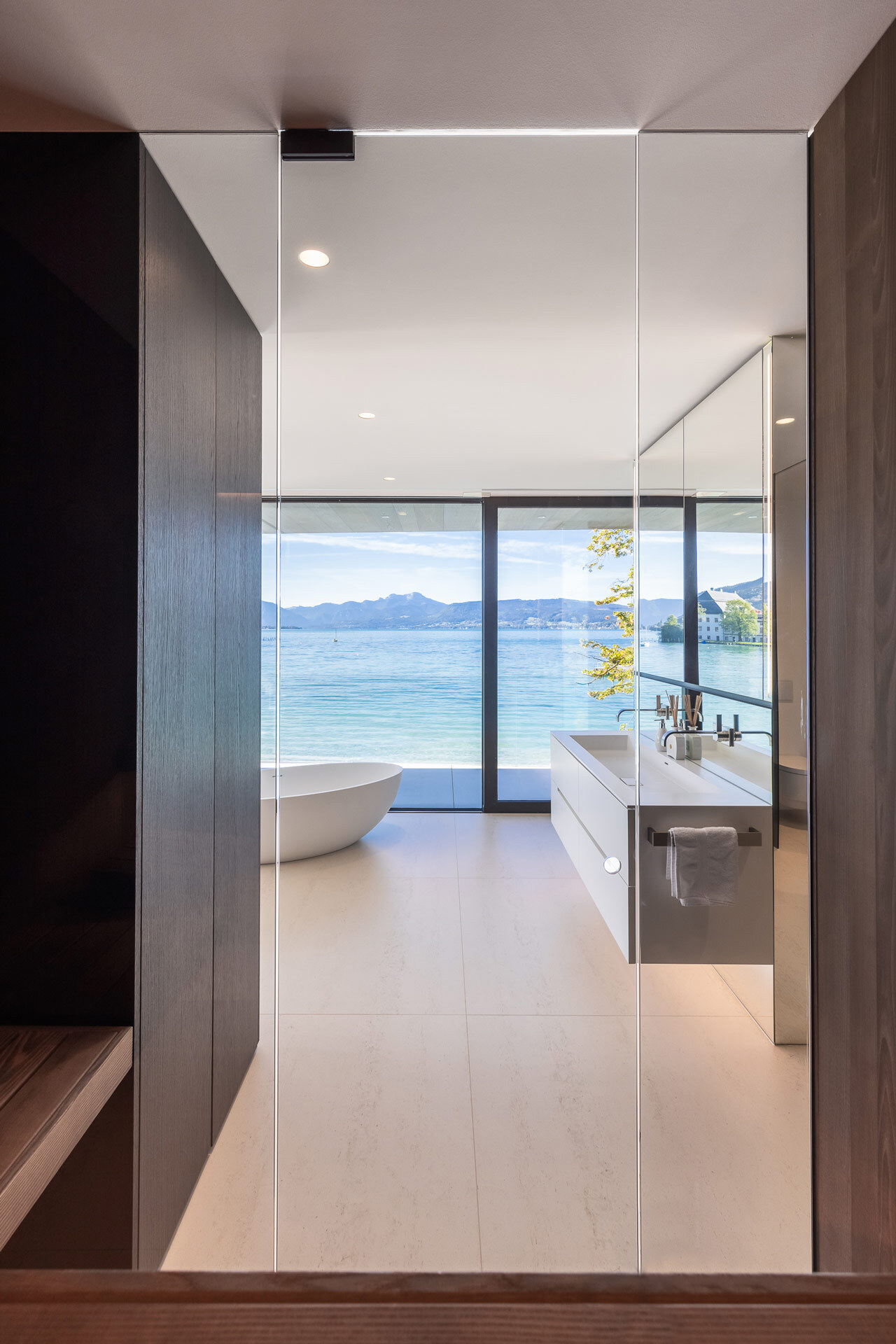 Private Spa im Badezimmer mit freistehender Badewanne und Sauna mit Panoramablick auf den See.