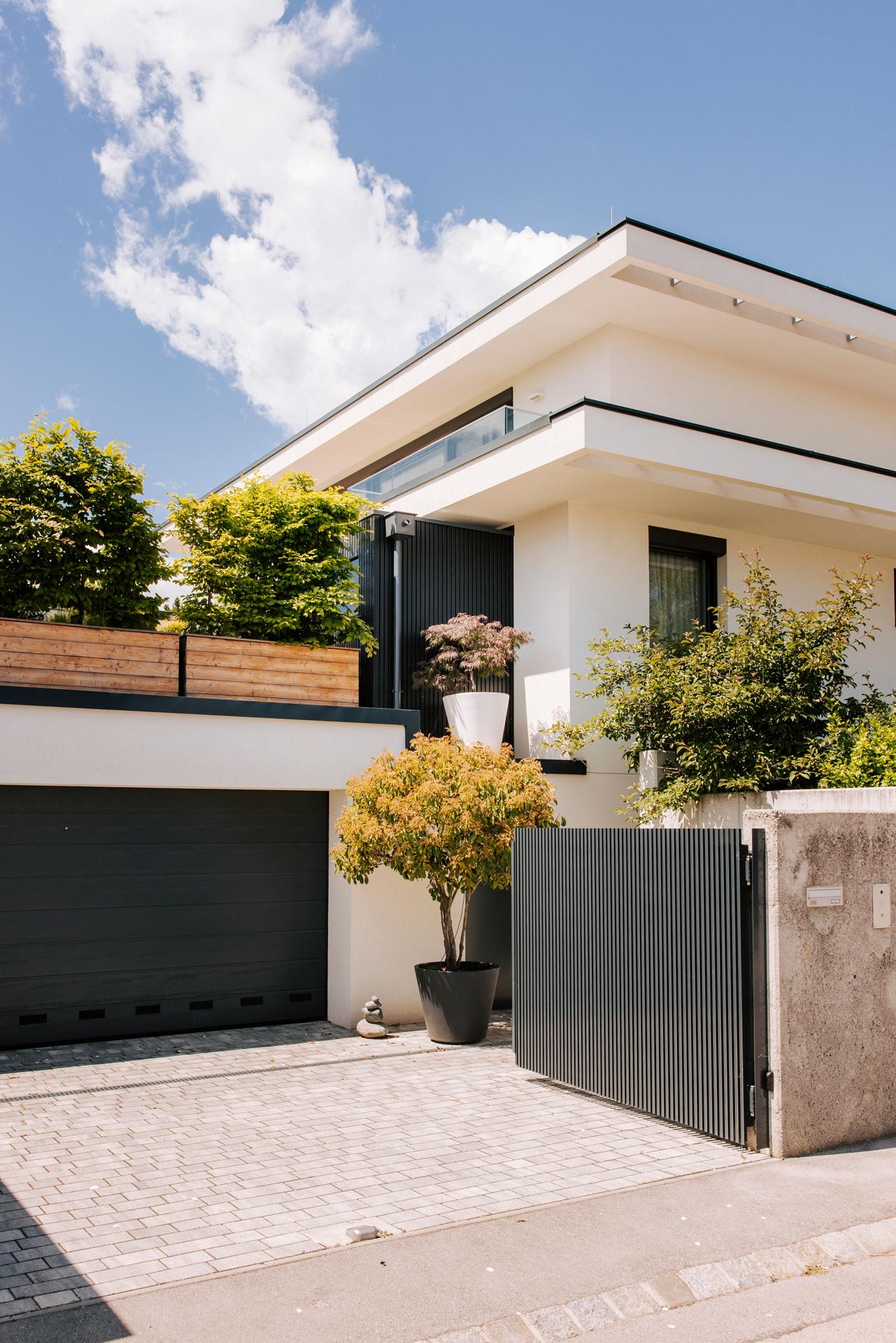 Schwarz verkleidete Outdoorsauna harmonisch eingebettet in die Architektur eines moderenen Hauses.