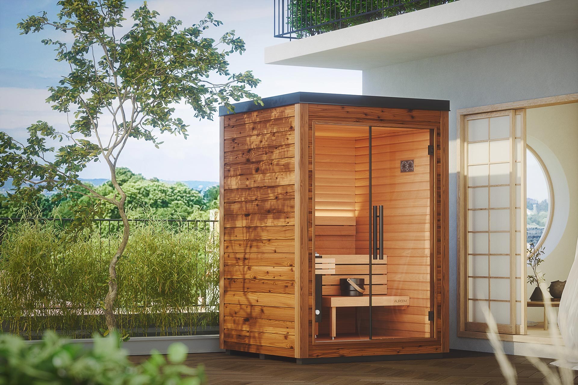 Kleine Espenholz-Sauna Mira der Saunalinie Auroom von Deisl, mit großer Glasfront und einer Außenverkleidung aus naturbelassener Thermofichte. Die Sauna steht auf einer Terrasse direkt neben einem Haus mit Blick ins Grüne.