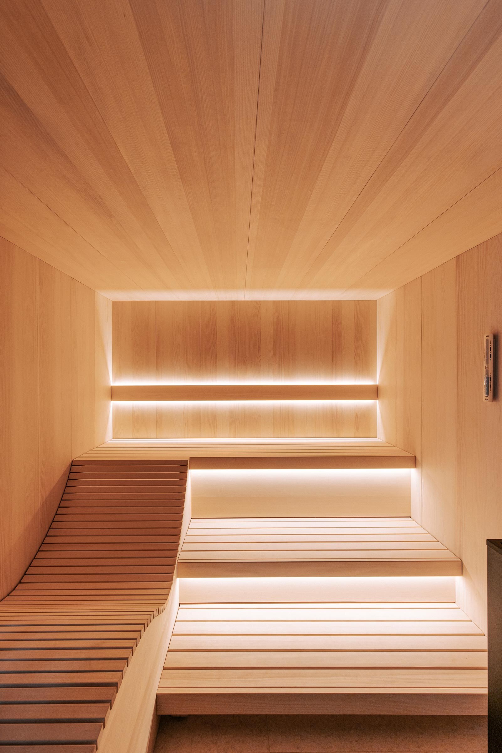 Leuchtende Sauna von Innen, aus gesaegtem Tannenholz, mit ergonomischer Saunaliege und Saunabaenken aus Espenholz, des oesterreichischen Saunaherstellers Deisl.
