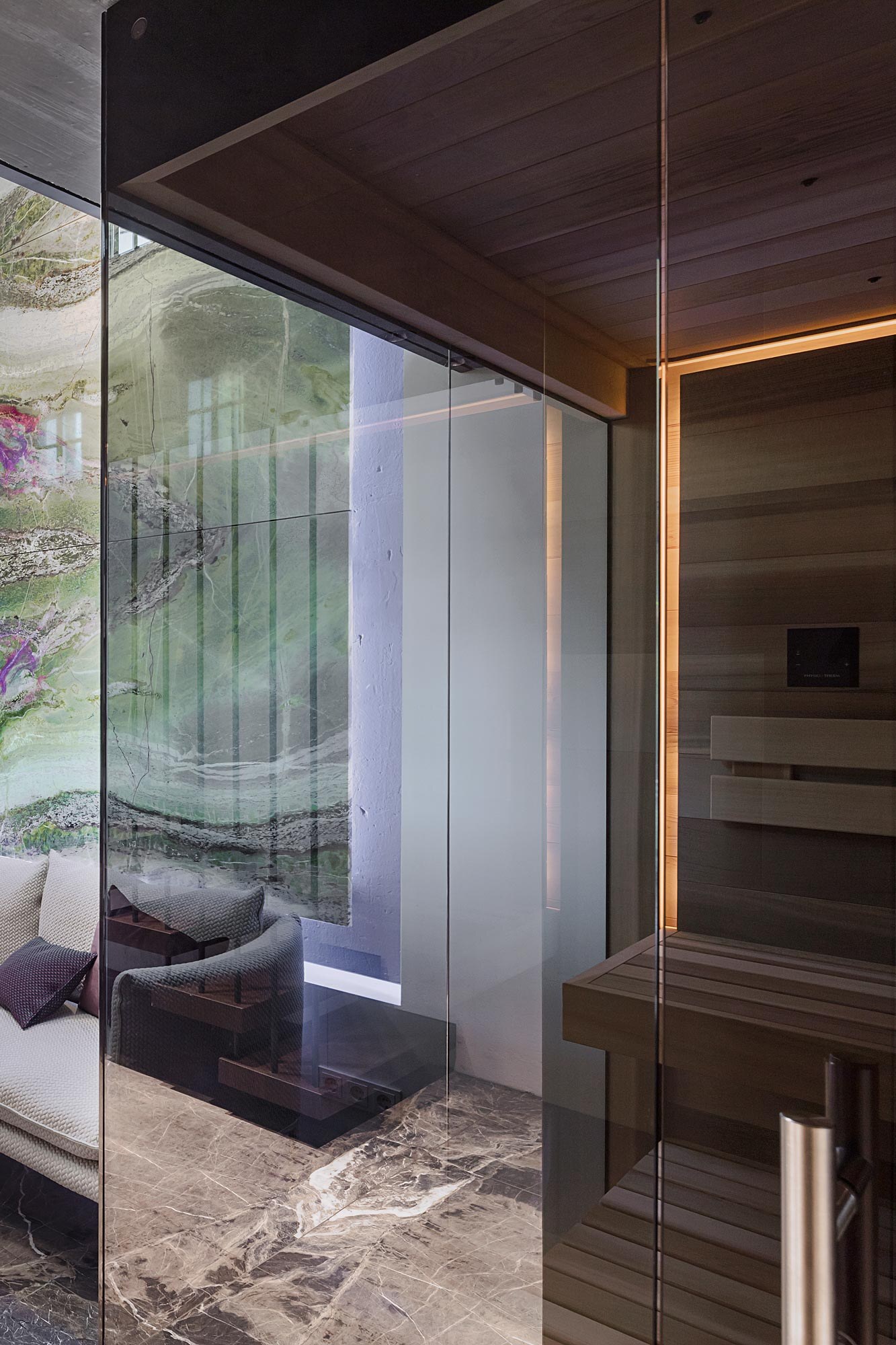 Moderne Infrarot-Sauna von Deisl aus massivem Zedernholz mit schwarz getoenter Uebereckverglasung und Stimmungslicht, passend fuer ein luxurioese Private-Spa.
