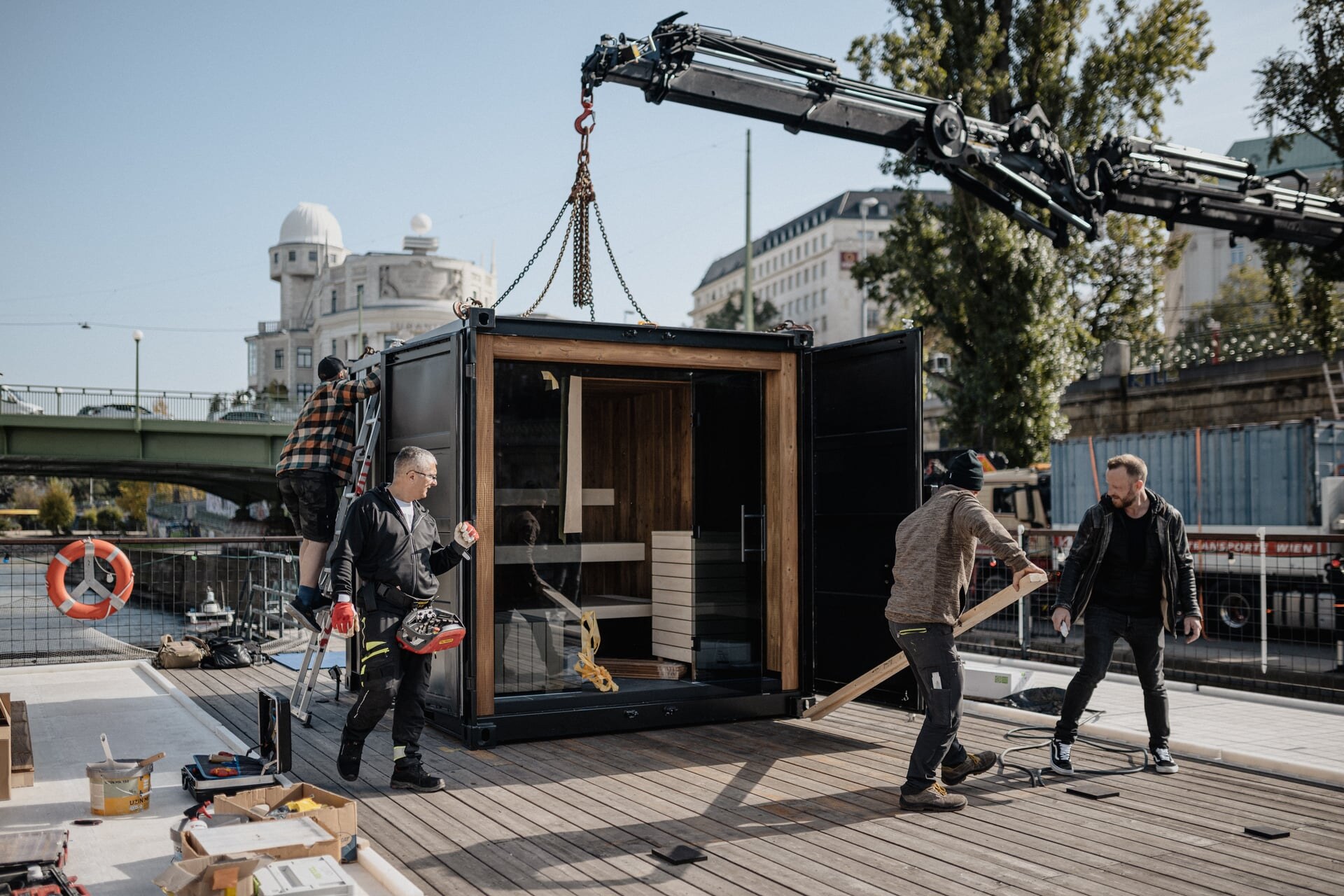 Deisl Montageteam beim Aufstellen einer Container-Sauna mit einem Kran am Deck des Badeschiff Wien.