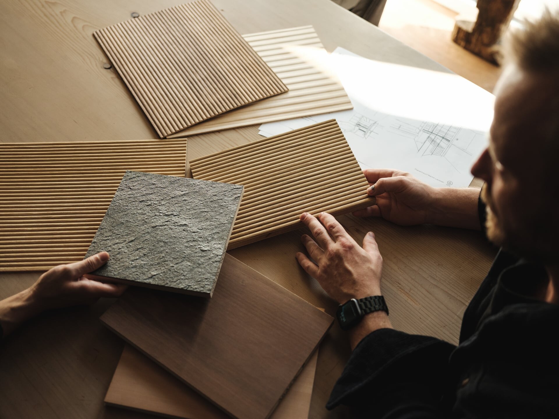 Auswahl mehrerer Holz- und Materialmuster auf einem Tisch mit Planer von Deisl.