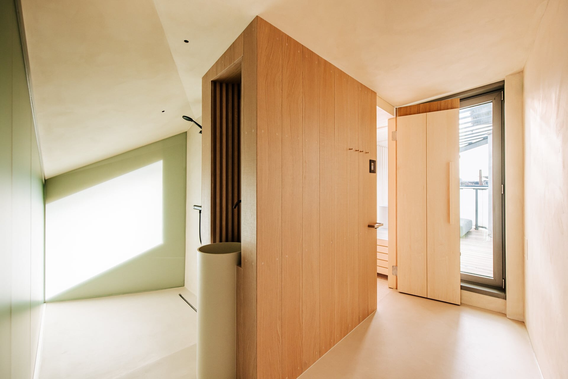 Luxus Sauna aus hellem Holz mit integriertem, rundem Waschtisch in einem minimalistischen Badezimmer mit bodenebener Dusche.