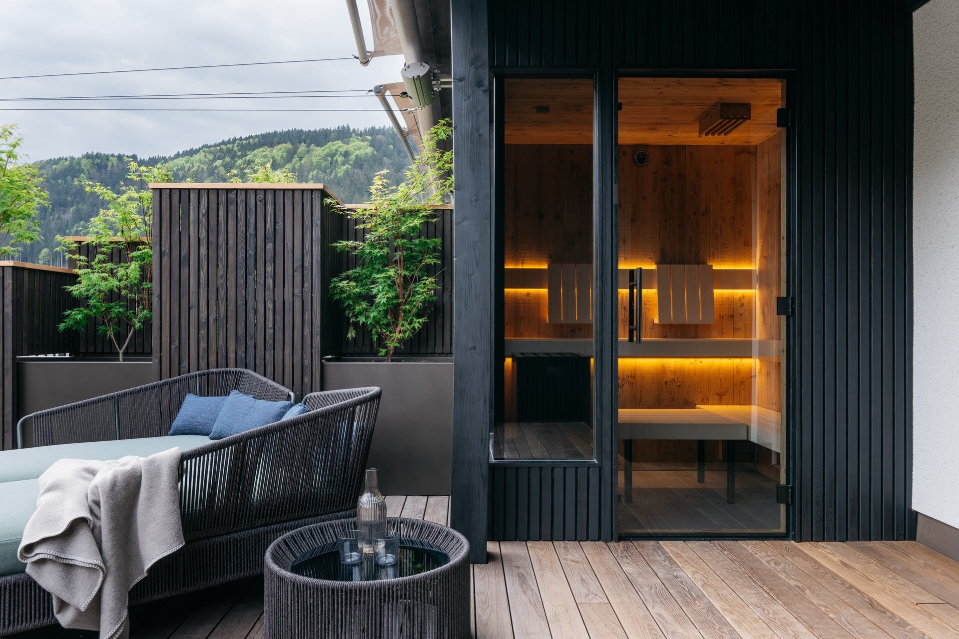 Modere Outdoor-Sauna mit schwarzer Holzverkleidung und Glaselementen auf der Terrasse im Refugium Lunz.