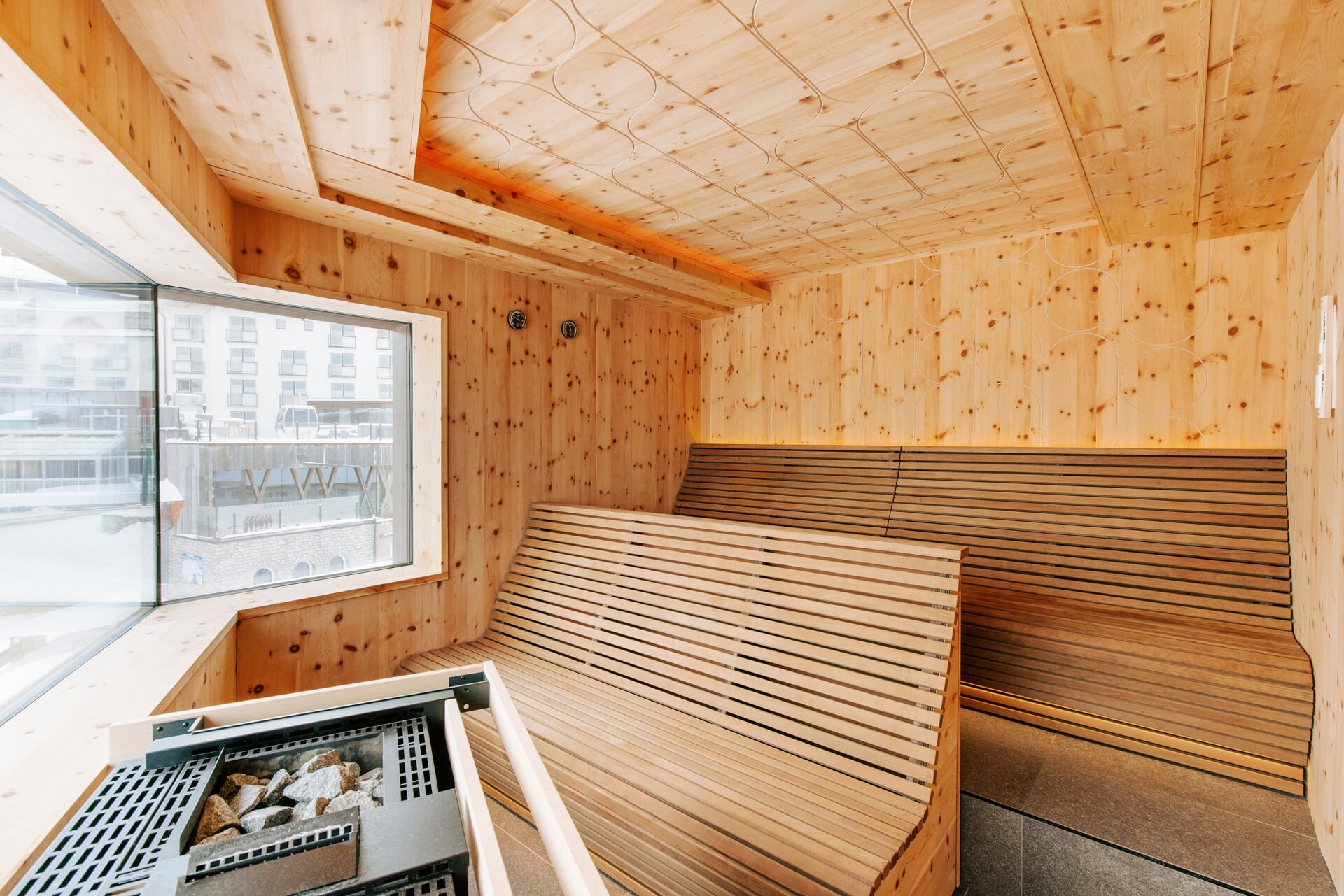 Moderne Zirnebsauna mit Panoramafenster, ergonomischen Bänken und Biosaunaofen im Wellnessbereich des Hotel Steiner.