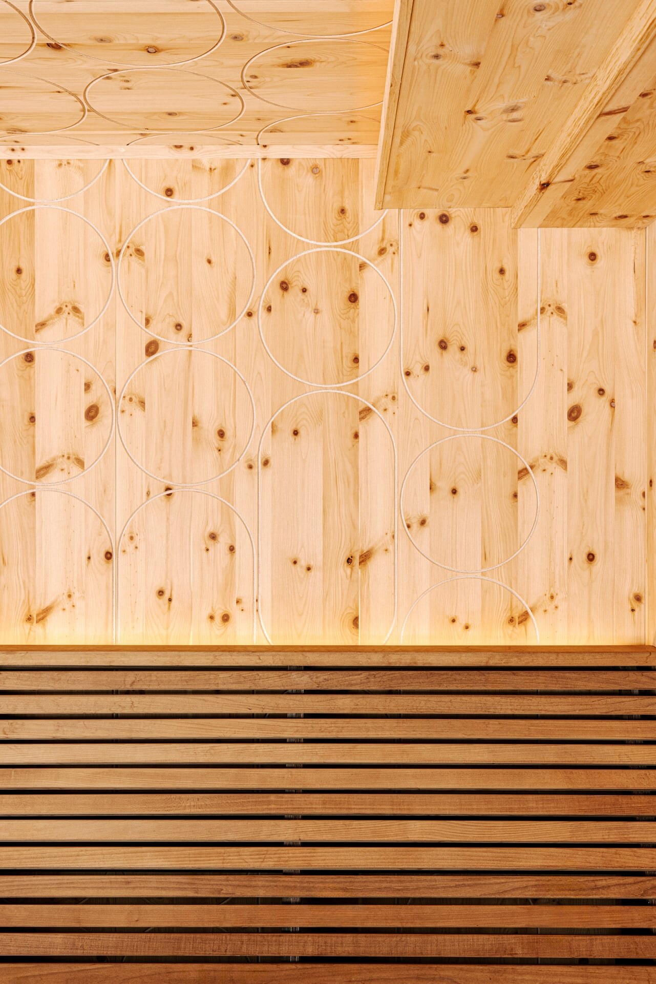Moderne Zirbensauna mit dekorativen Fräsungen an der Wand und dunkler Saunabank..