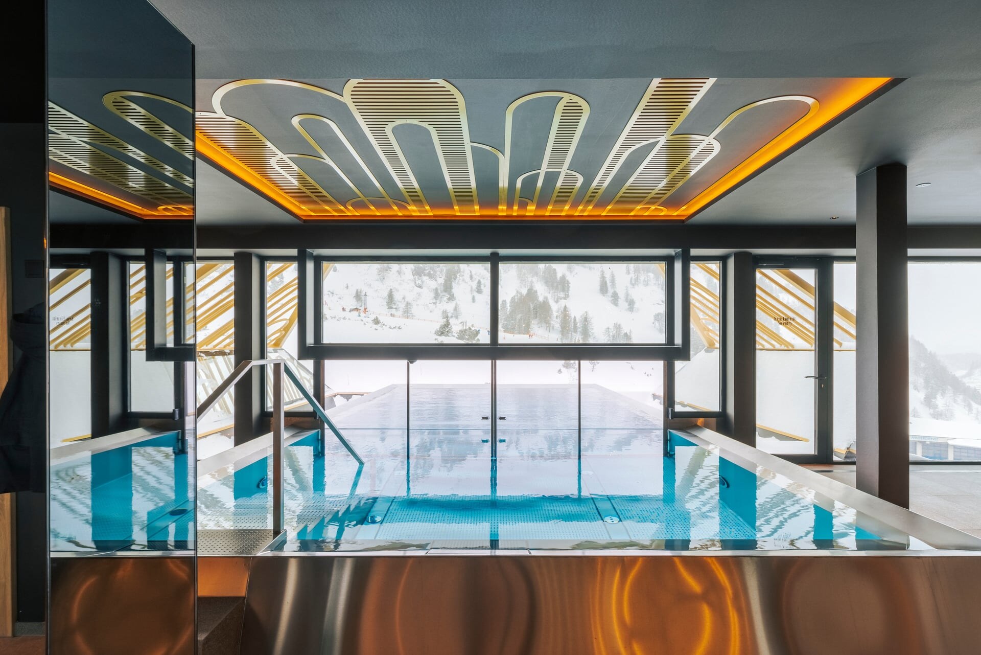 Moderne Indoor-Outdoor Pool mit goldenen Zierelementen im Superior Hotel Steiner.