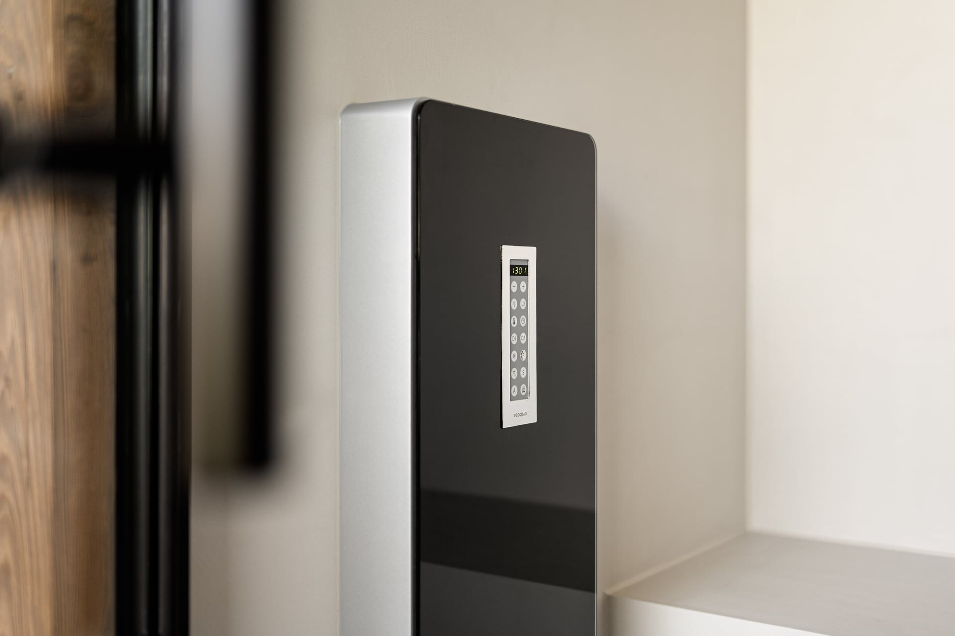 Detail eines modernen, schwarzen Dampfmoduls mit integriertem Dampfgenerator in einer minimalistischen Dampfdusche aus hellgrauem, fugenlosen Mikrozement.