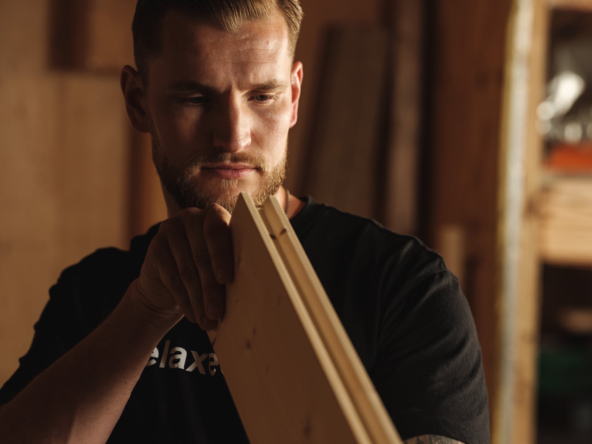 Ein Tischler prüft die Qualität einer Holzbohle für eine Sauna in der Manufaktur von Deisl.
