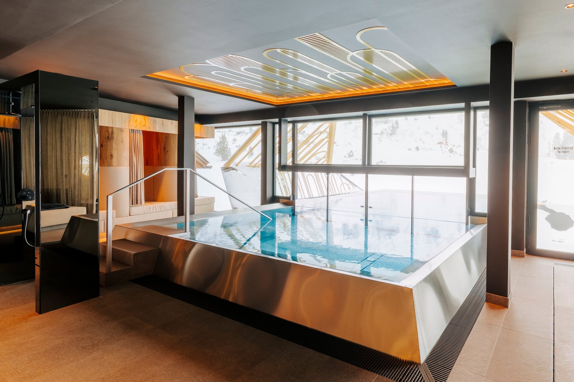 Moderne Indoor-Outdoor Pool mit goldenen Zierelementen im Superior Hotel Steiner.
