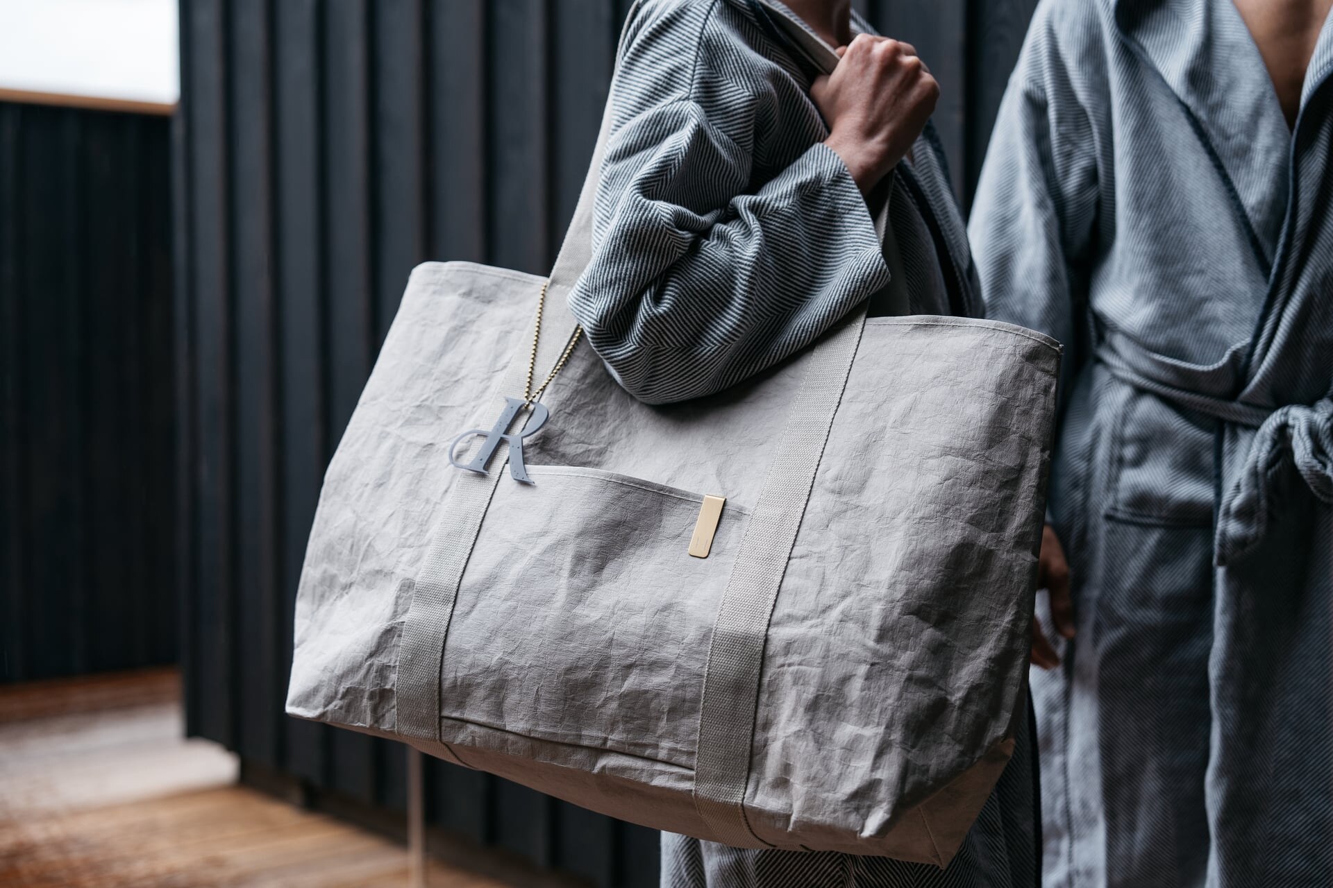 Zwei Gäste im Bademantel mit Badetasche im Outdoor-Wellnessbereich des Refugium Lunz.