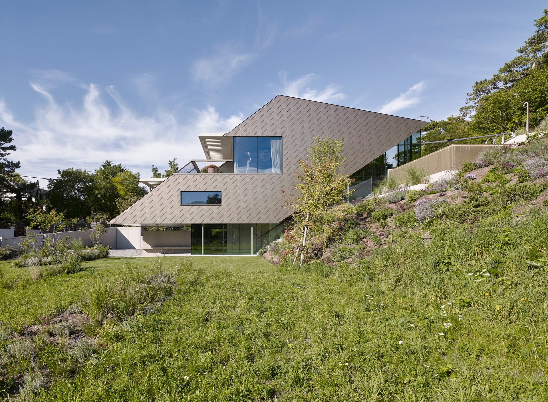 Einfamilienhaus in moderner Architektur mit braungold verkleiderter Fassade und Garten