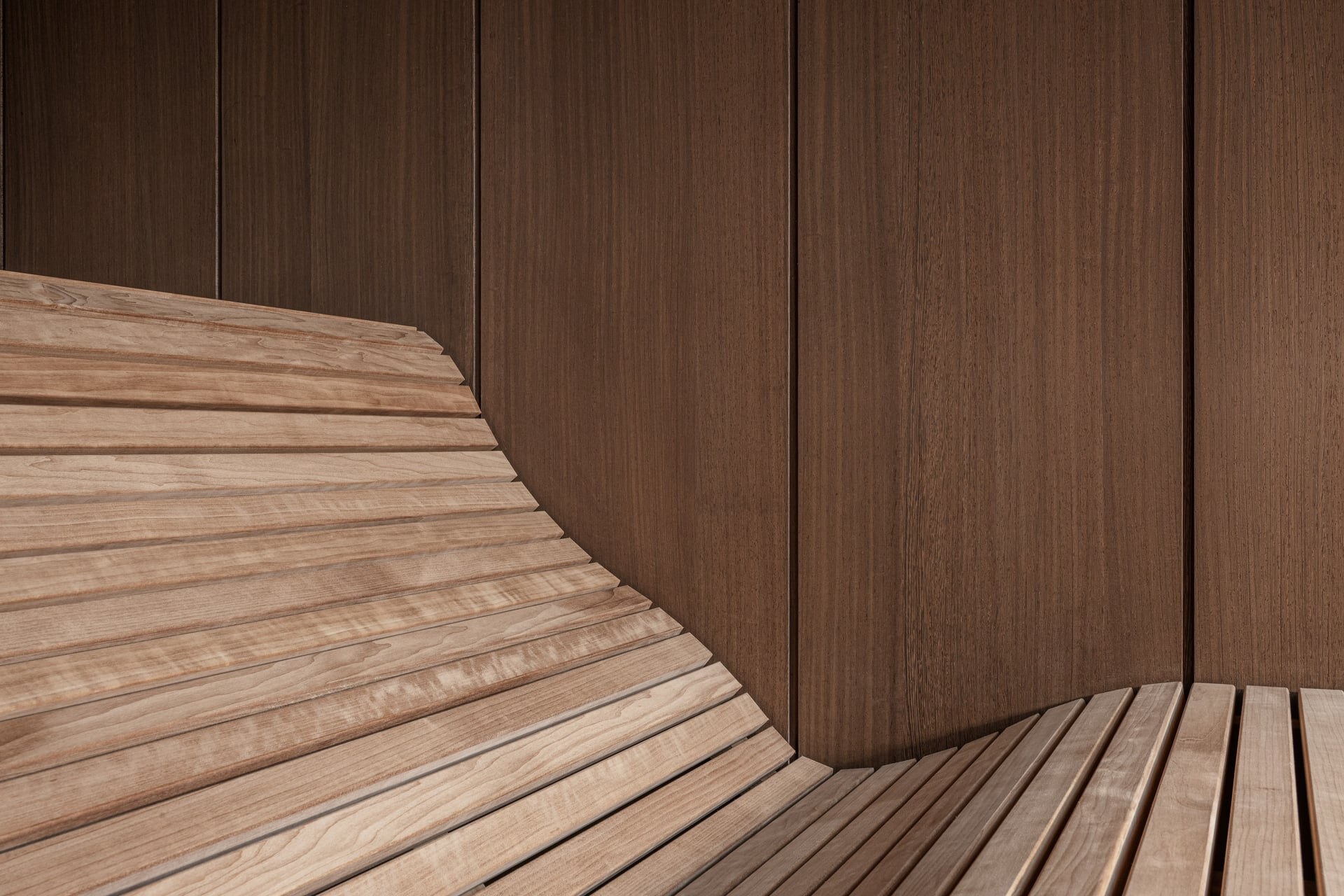 Ergonomische Saunabank aus dunklem Holz im Wellnessbereich des Kurblhof.