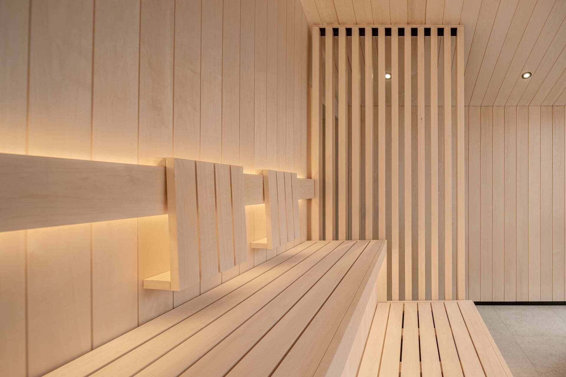 Hotelsauna aus hellem Espenholz in minimalistischem Design mit Sichtschutz aus Holzlamellen.