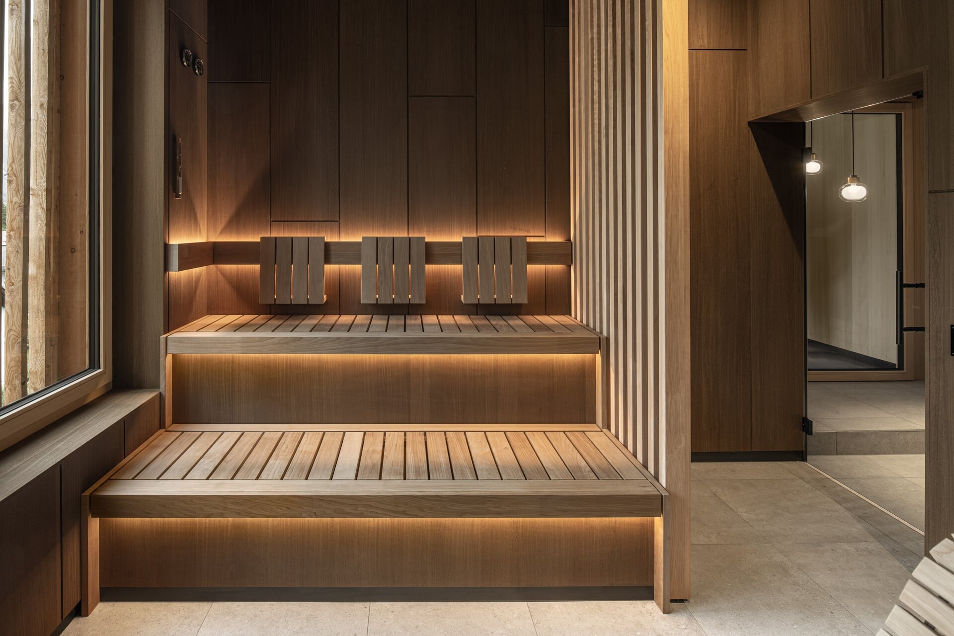Elegante Luxussauna aus dunklem Holz mit seitlichem Sichtschutz aus Holzlamellen im Wellnessbereich des Naturhotel Kurblhof.