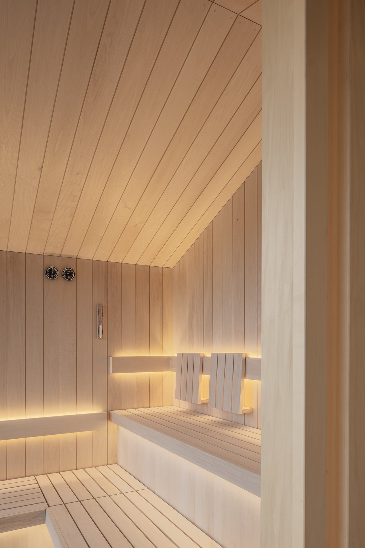 Minimalistische Sauna unter Dach aus hellem Holz mit indirekter Beleuchtung im Naturhotel Kurblhof.