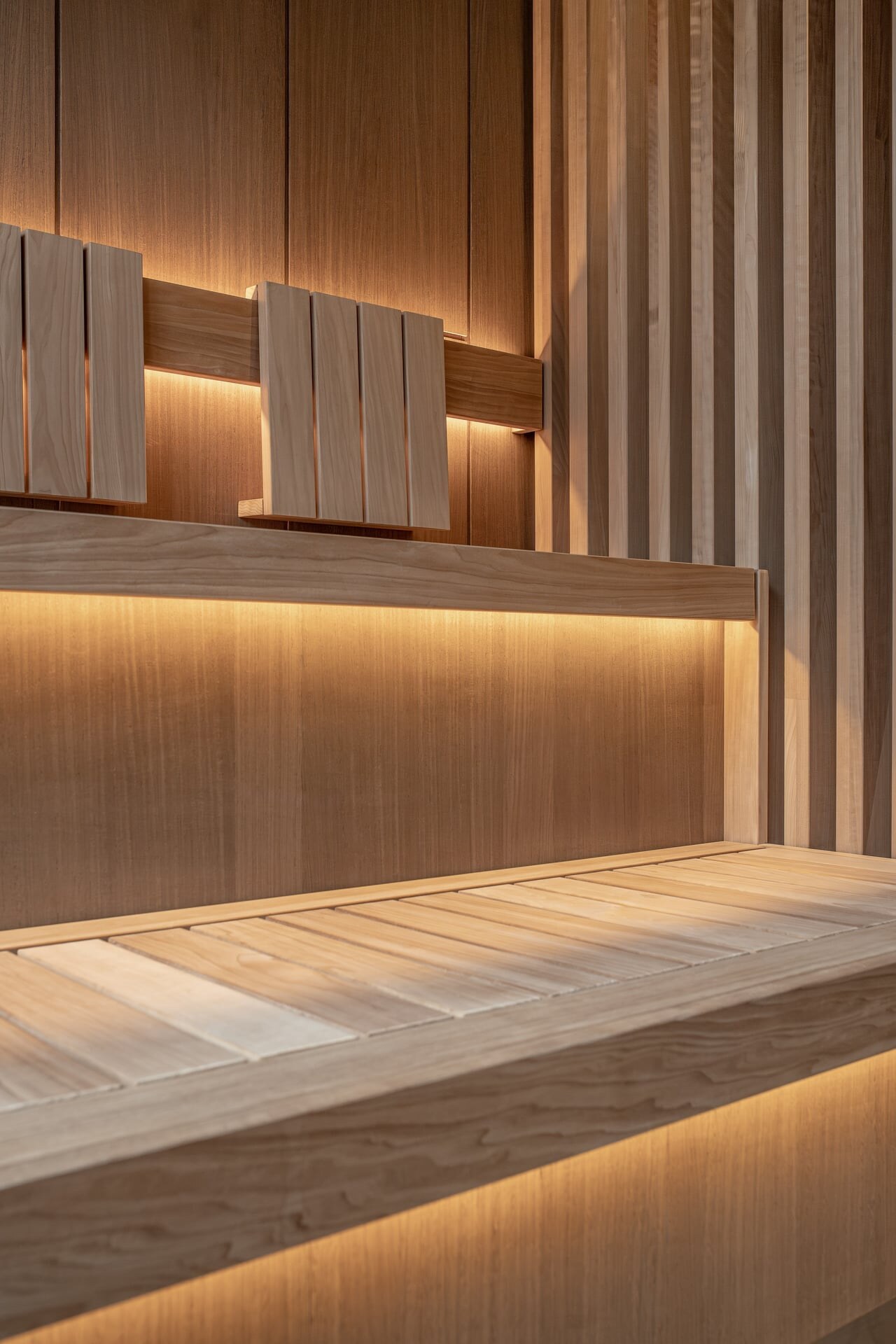 Moderne Design-Saunabank aus Thermoesche mit seitlichem Sichtschutz und indirekter Beleuchtung.