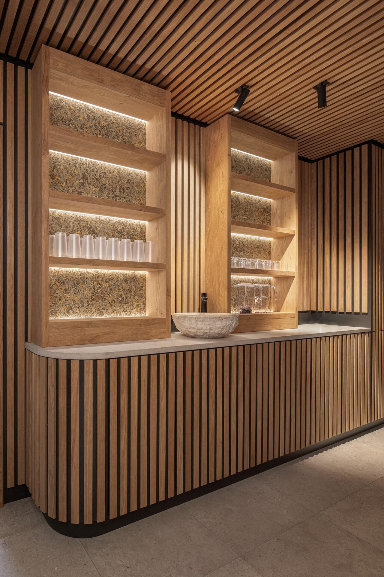 Moderne Vitaminbar aus Eichenholz mit beleuchteten Wandpaneelen aus gepressten Almkräutern im Spa-Bereich des Naturhotel Kurblhof.