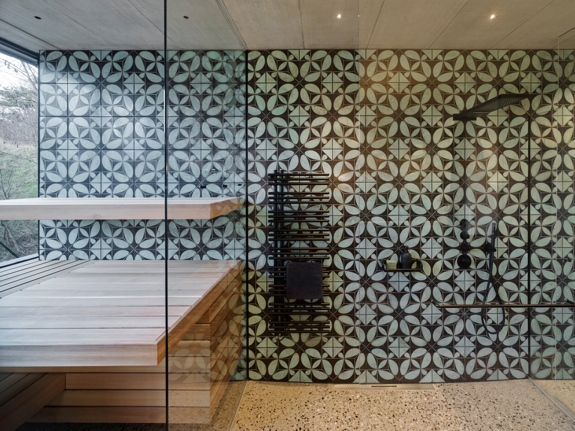 Moderne Sauna aus Glas und Zedernholz im Badezimmer mit einer türkis-schwarzen Fliesenwand von Karak.