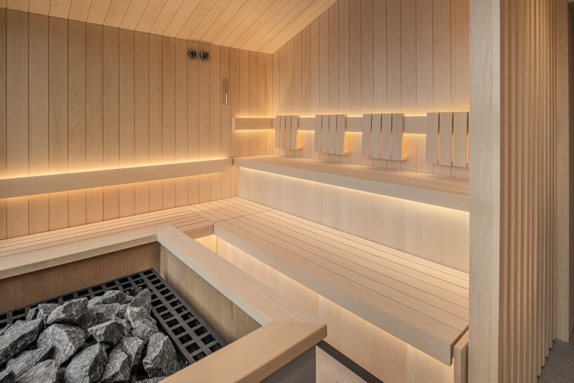 Minimalistische Sauna nach Maß aus hellem Espenholz unter einer Daschschräge mit dezenter Beleuchtung.