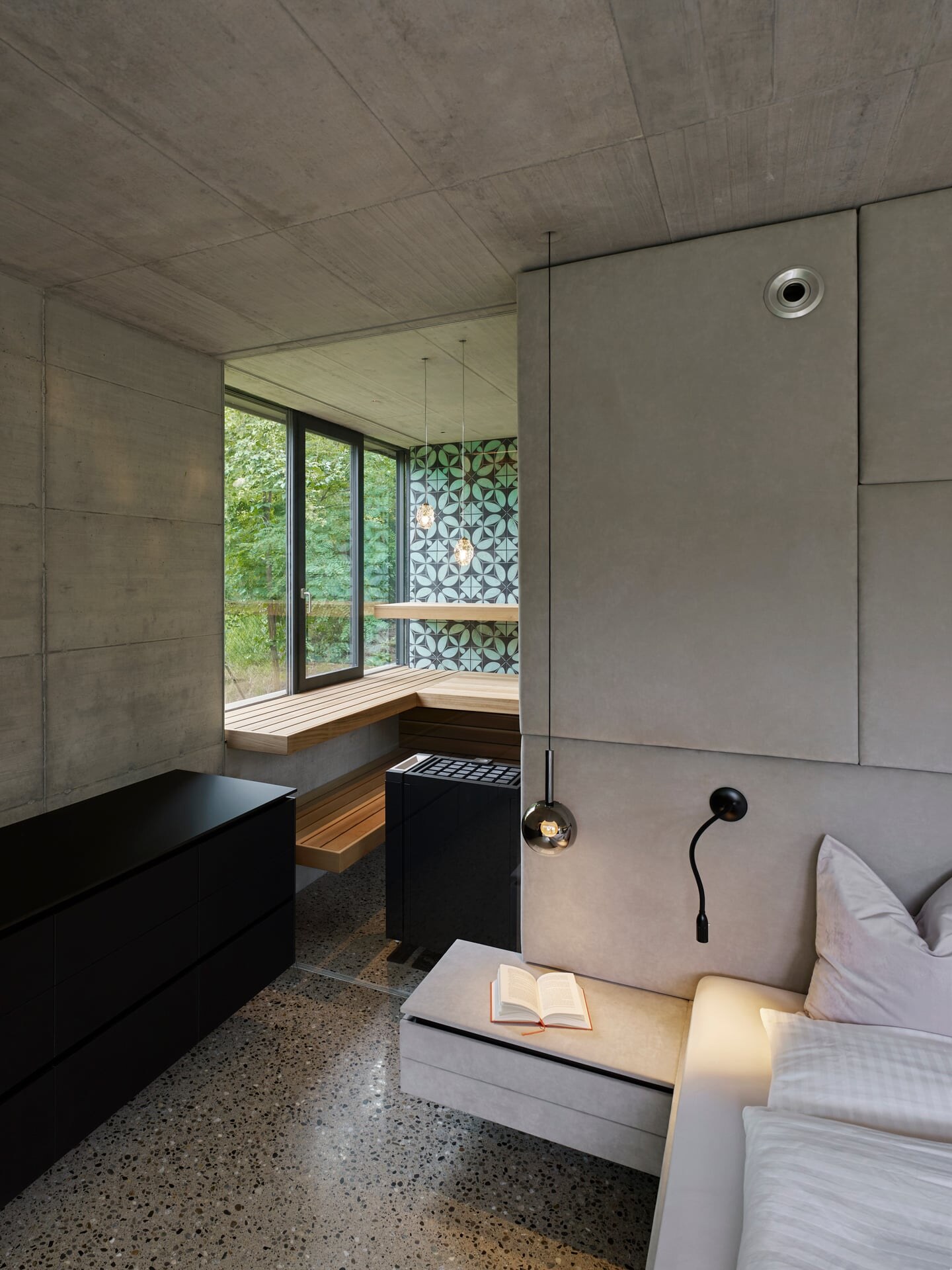 Im modernen Schlafzimmer integrierte Sauna mit raumhoher Glasfront und einem Fenster ins Grüne.