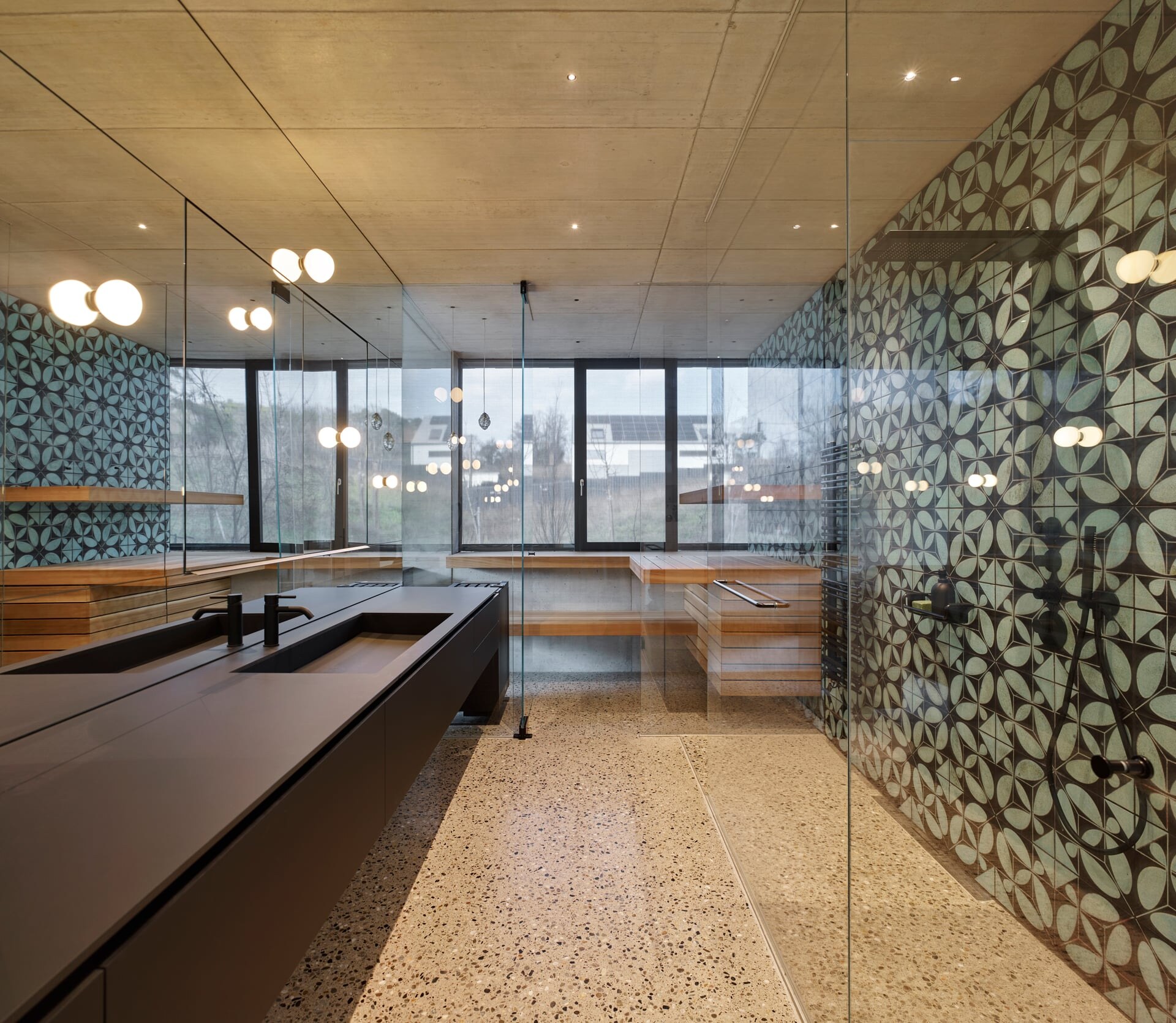 Vollverglaste Sauna nach Maß im modernen Badezimmer mit Terrazoboden und Sichtbetondecke.