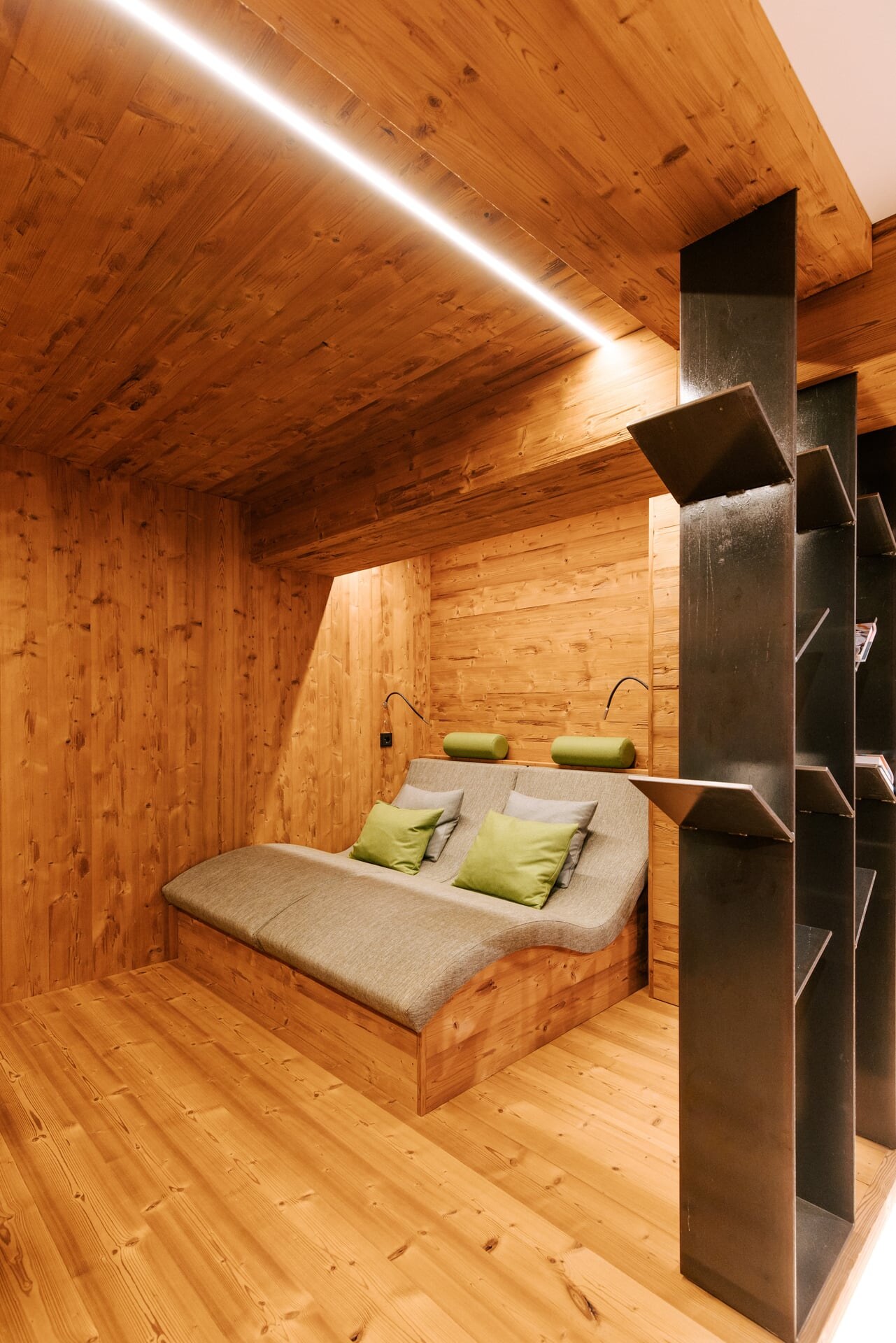 Ergonomische Ruheliegen im Wellnesskeller in modern-alpinem Stil mit Magazinständer aus Metall als Sichtschutz.