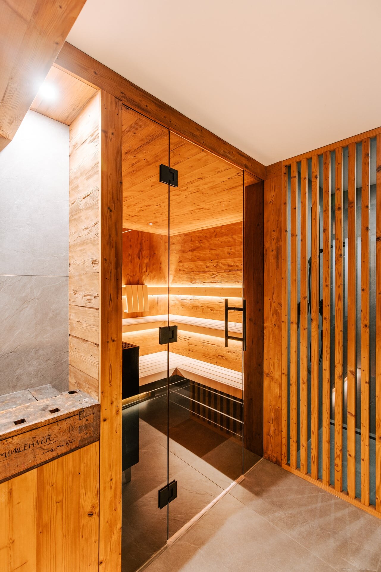 Moderne Sauna aus Fichtenholz in rustikalem Design mit getönter Glasfront in einen Keller integriert.