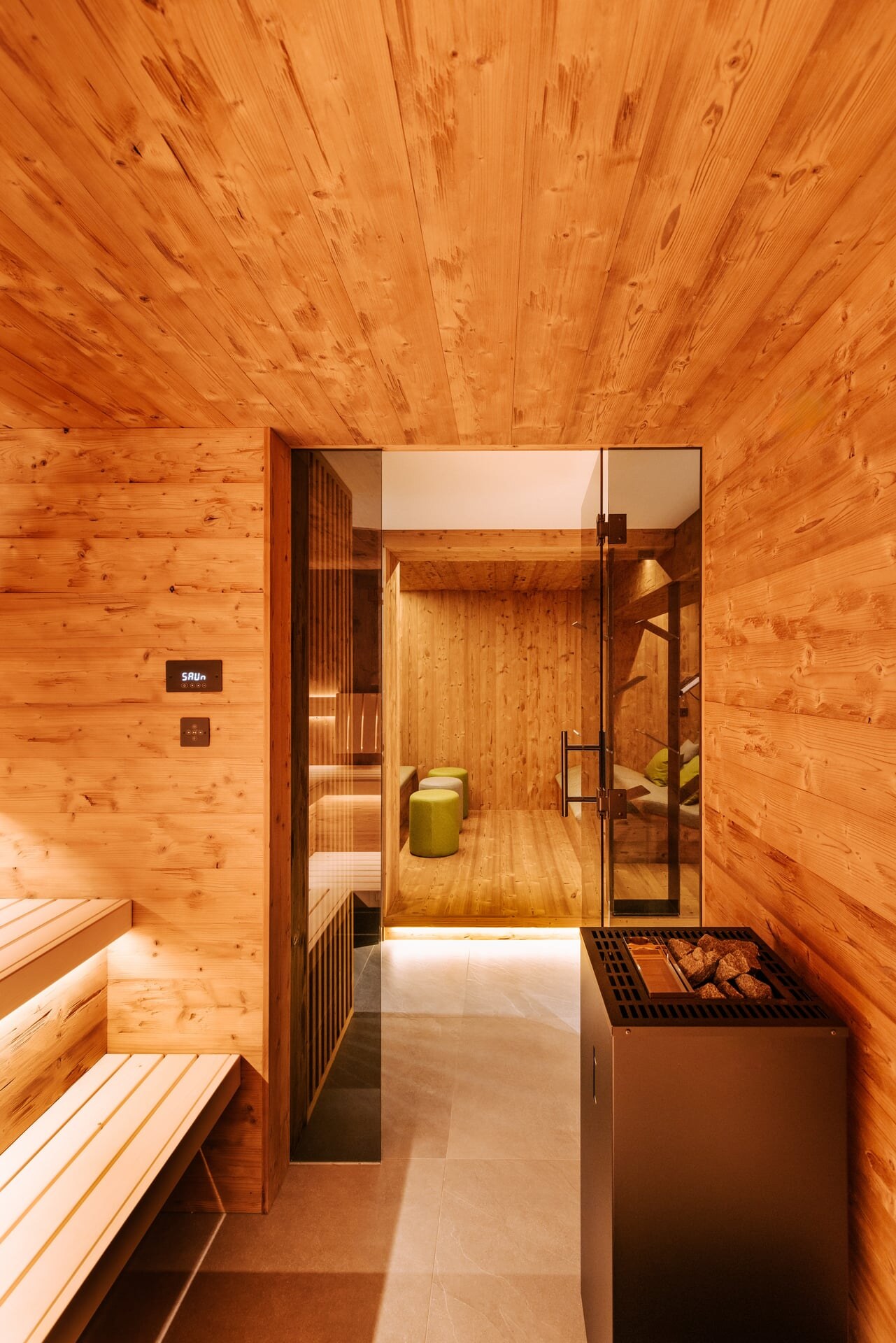 Moderne Sauna in rustikalem Thermoholz mit Blick in einen Wellnessbereich.