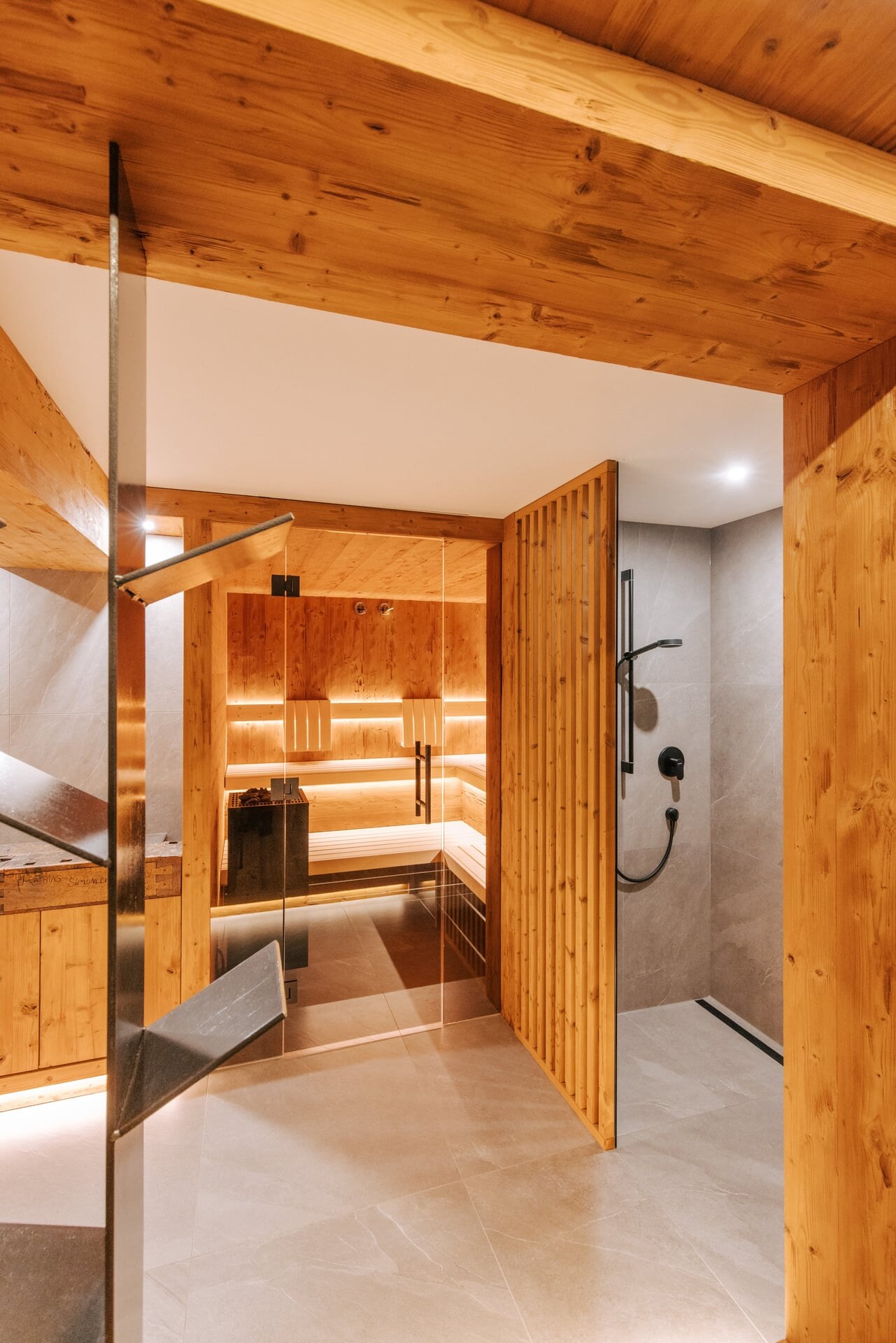 Modernes Private Spa mit Sauna in rustikal-alpinem Stil aus gehacktem Holz, grauen Fliesen und einer bodenebenen Dusche.