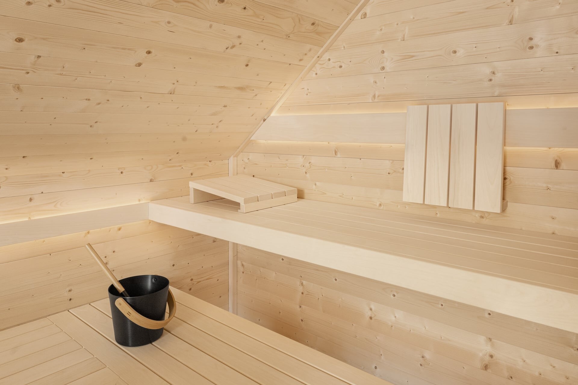 Saunabank in modernem Design in einer Sauna aus hellem, massiven Fichtenholz, eingebaut unter einer Dachschräge