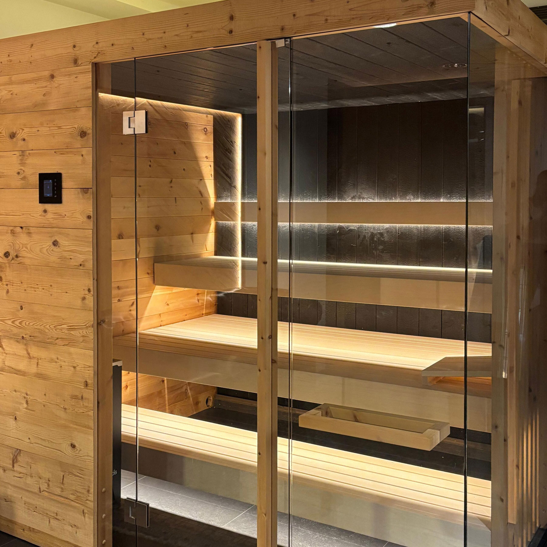Große Zirbensauna für 4 bis 5 Personen als Ausstellungsstück im Showroom Liezen mit Glasfront und schwarzer Lärchenverkleidung.