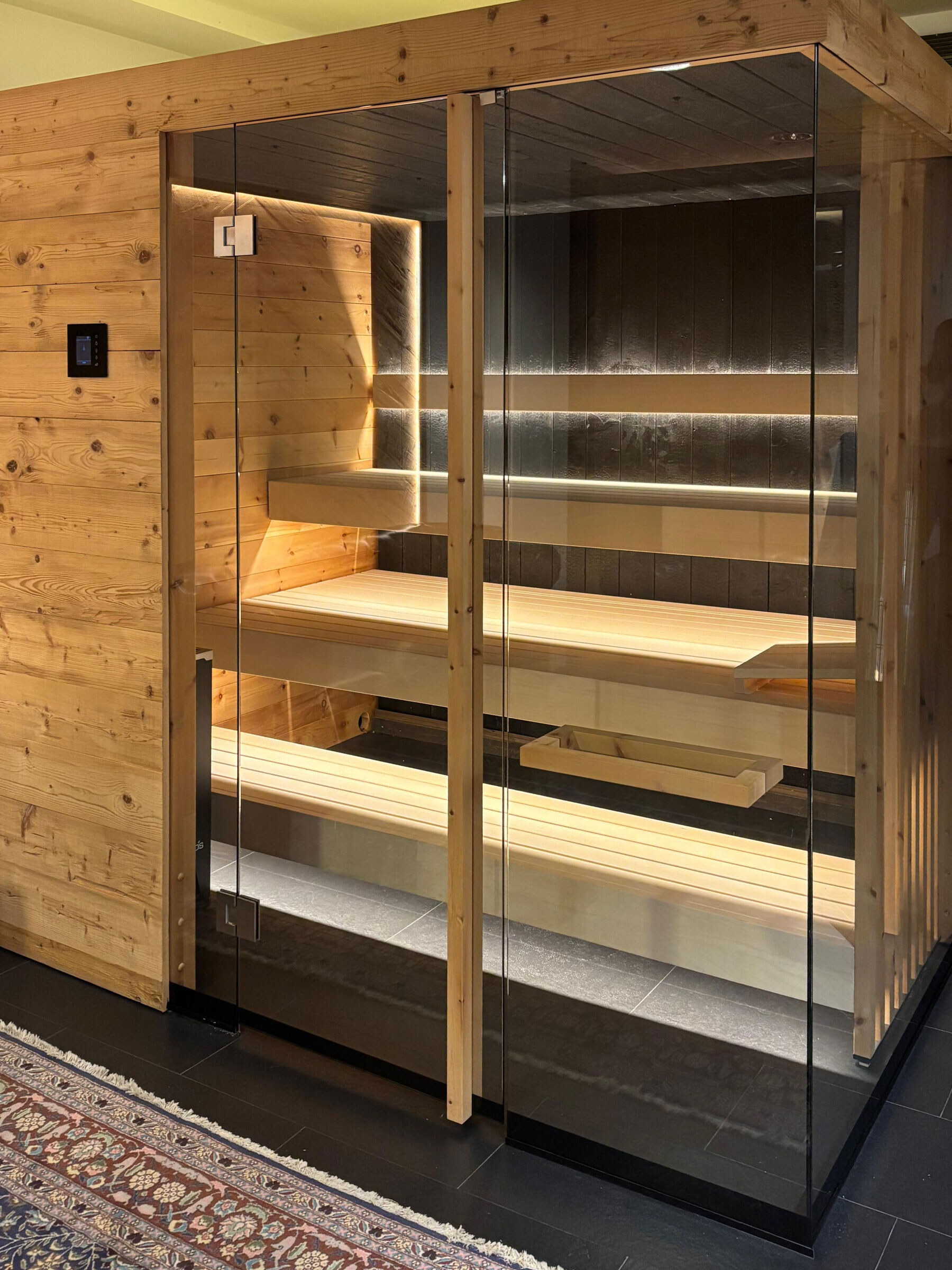 Große Zirbensauna für 4 bis 5 Personen als Ausstellungsstück im Showroom Liezen mit Glasfront und schwarzer Lärchenverkleidung.